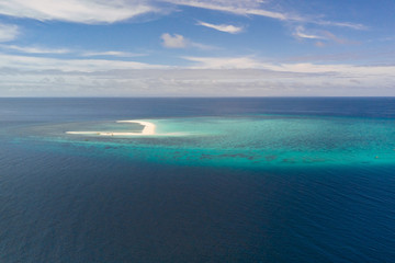 Atoll with an island of white sand. Sand beach island on a coral reef, top view. Tourist route on Camiguin Island, Philippines.