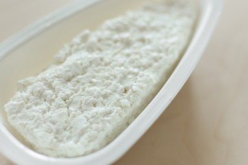 Cottage cheese in a white bowl closeup. Organic farming homemade cottage cheese.
