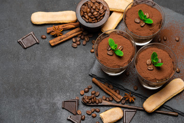 Frame made of Classic tiramisu dessert in a glass and savoiardi cookies on dark concrete background