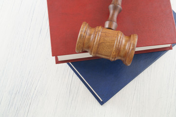 Judge gavel and blue and red legal books on wooden table