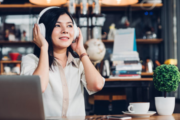Lifestyle freelance woman he using earphones listening music during working on laptop computer