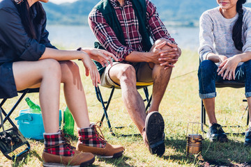 Young couple and friend sitting on chair discuss together camping