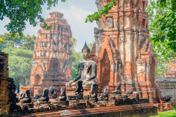 Only intact ancient Buddha statue among the destroyed statues in Ayutthaya historical park, Thailand. - obrazy, fototapety, plakaty