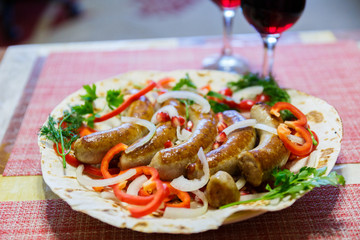 Grilled pork sausages on pita bread with vegetables are served with red wine. Oktoberfest food, the concept of the pub