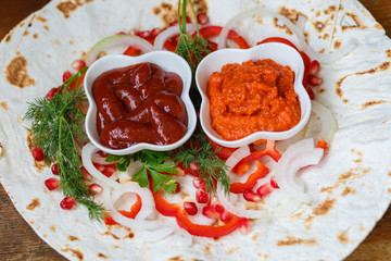 Red bell peppers, onions, pomegranate and parsley on lavash for roasted meat, sausages or sausages are served with ketchup and Armenian snack Aivar. The view from the top.