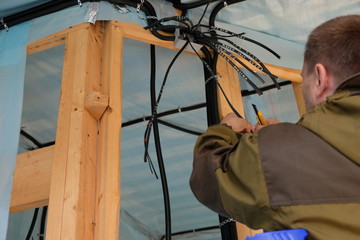 Electrical cables are fixed inside the frame house. Made wiring. A working electrician does his job.