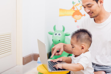 Father acting Mom feeding milk his son baby 1 year old while working on laptop computer