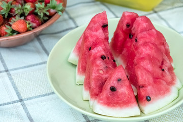 Fresh slices of red watermelon on a plate. Strawberries in a plate. Fruit on a white tablecloth...