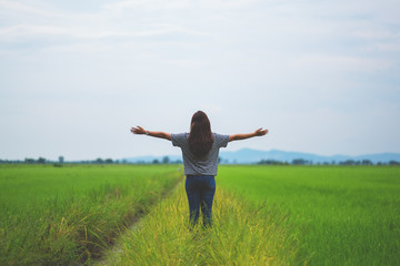 A woman standing and stretching arms in a beautiful rice field with feeling relaxed and fresh