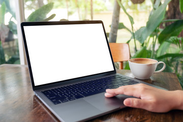 Mockup image of a woman using and touching laptop touchpad with blank white desktop screen while drinking coffee on wooden table