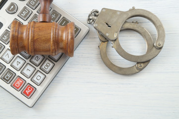 Wooden gavel, calculator and handcuffs on white table. financial fraud concept