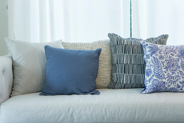 close up of set of white, blue and grey pillows on white Sofa