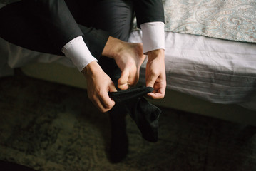 Man putting socks on his feet close-up in bedroom