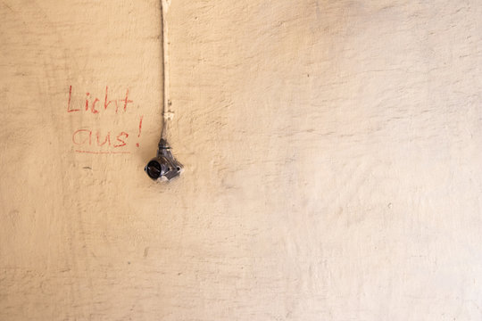 Alter schwarzer Lichtschalter f&uuml;r eine Au&szlig;enleuchte mit einem handschriftlichen Hinweis "Licht aus!" zum Strom sparen