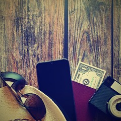 Items for summer vacation: a camera, passport,smartphone, money, hat, sunglasses. Wooden background, top view with Copy space. Beautiful summer concept for travel and summer vacation.