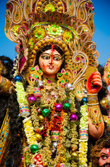 Golden and colorful statue of ten handed goddess Durga being worshiped with flower on the occasion of durga puja in Kolkata, India.