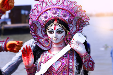 White and purple statue of Hindu goddess Saraswati being worshipped with flower in Kolkata , India.