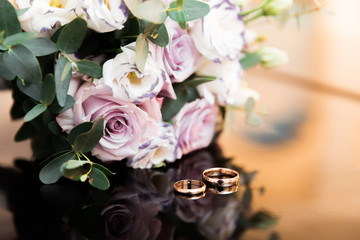 wedding rings lie on a beautiful bouquet as bridal accessories