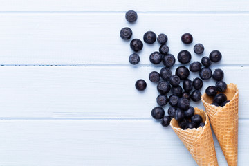 Fresh blueberries, in a heart shaped bowl on a wooden background.