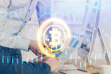 Crypto currency theme hologram with businessman working on computer on background. Concept of...