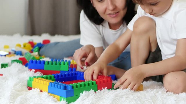 The child and his mother play meccano colored blocks on the bed. The concept of a happy family.