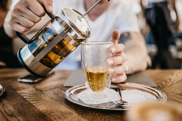 pouring green tea into a glass cup in a cafe