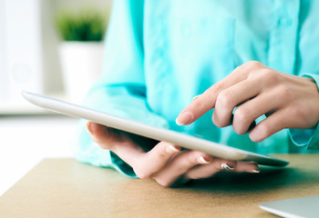 Close-up of female hands working with tablet computer. Woman using social network, texting and blogging.