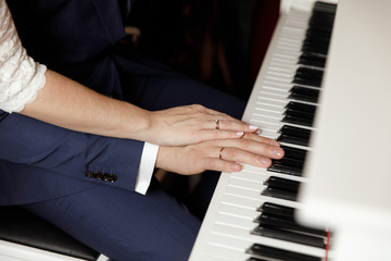 Fototapeta premium Groom and and bride hands with rings. On piano, close up