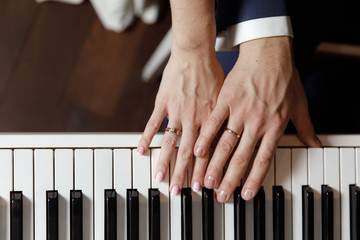Groom and and bride hands with rings. On piano, close up