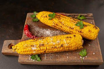 Grilled corn with greens and salt on the background of concrete, snack or dinner, breakfast