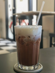 Iced chocolate with milkshake on wooden table in cafe background.