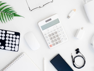 top view of office desk table with  calculator, notebook, plastic plant, smartphone and keyboard on white background, graphic designer, Creative Designer concept.