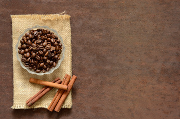 Coffee beans with fragrant cinnamon on burlap. Rusty, scratched metal and coffee