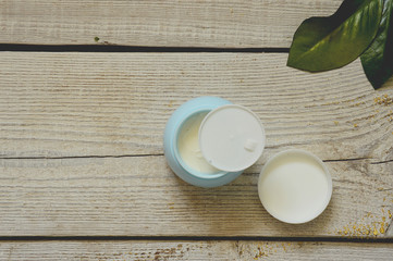 face cream on white wooden table background. Cosmetic cream container on white wooden background with flowers. Face cream banner.