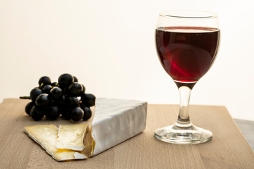 glass of red wine and grapes on white background