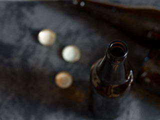 Empty beer bottles and lids on the table. Alcoholism