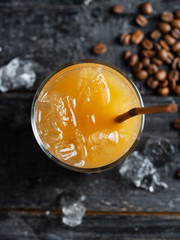 Summer drink iced coffee in a glass on a dark old wooden table with coffee beans
