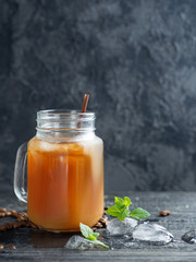 Glass jar of iced coffee on a dark wooden table close-up