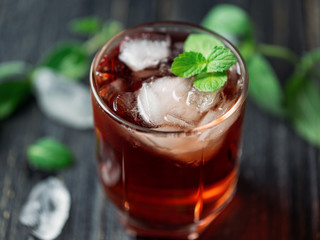Red cocktail with mint in a glass on a dark wooden table