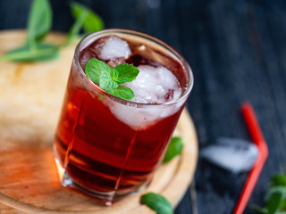 Red cocktail with mint in a glass on a dark wooden table