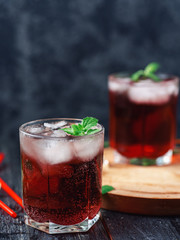 Two glasses of red cocktail with ice and mint close-up