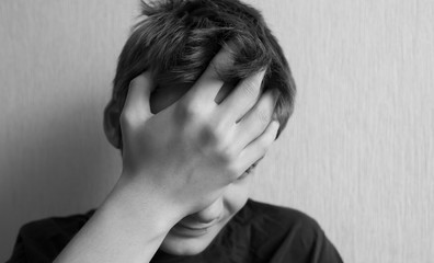 Teen boy covers his face with his hand and screams