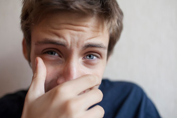 Teen boy covers his face with his hand and screams
