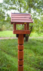 Wooden house for birds tits pigeons feeder with large windows stands in the woods park