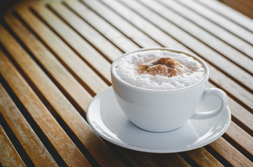 close up modern hot black coffee the cappuccino on wood background with coffee bubble foam pattern and texture in white cup looking and feel so delicious on glasses table in coffee shop.