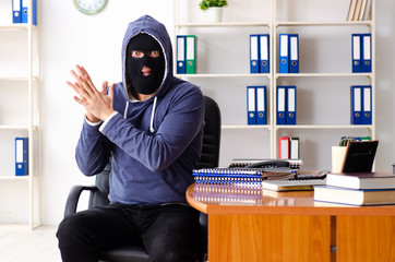Male thief in balaclava in the office 