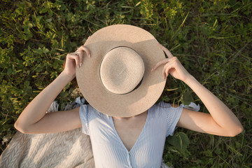 Happy young woman is lying in the park on the green grass. Portrait view from above