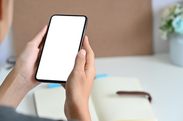 Cropped shot woman using mockup smartphone on office desk.