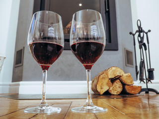 Glasses of wine near the fireplace with firewood.Holiday and cozy concept.