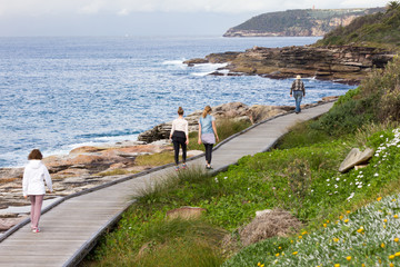 Naklejka premium People walking along the boardwalk on the New South Wales coastline near Freshwater Bay, Sydney, Australia
